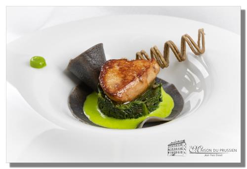 a plate of food with a piece of meat and vegetables at Hôtel La Maison du Prussien in Neuchâtel
