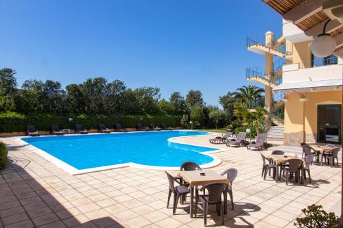 un resort con piscina, tavoli e sedie di Hotel Cala Dei Pini a Porto Pino
