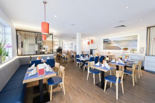 un restaurant avec des tables et des chaises bleues dans l'établissement Hotel Ostseewoge, à Graal-Müritz