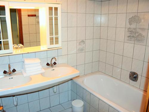 uma casa de banho com um lavatório, uma banheira e um espelho. em Tennladen Apartments em Niederau
