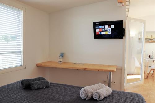 ein Schlafzimmer mit 2 Handtüchern auf einem Bett und einem TV an der Wand in der Unterkunft Inselappartement Reichenau in Reichenau