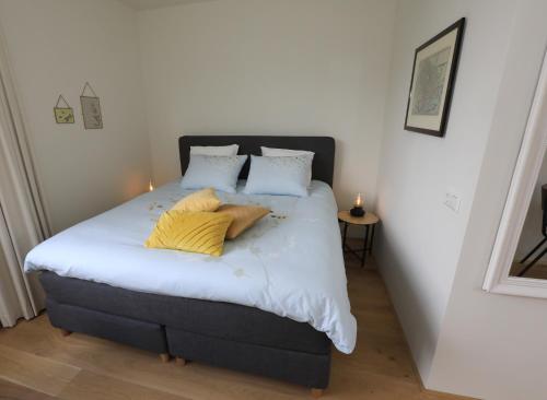 een slaapkamer met een bed met witte lakens en gele kussens bij B&B De Zwanebloem in Amsterdam