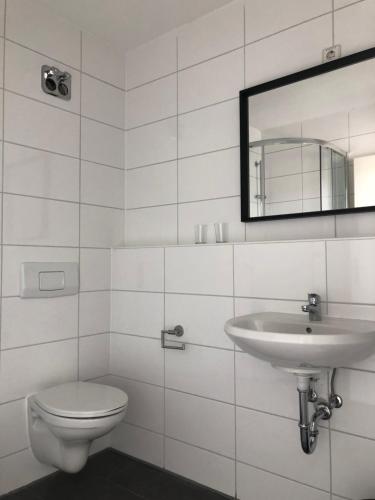 a white bathroom with a sink and a toilet at Libarty Appartments in Kornwestheim