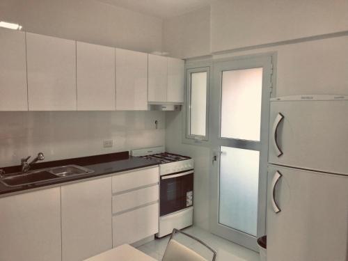 a kitchen with white cabinets and a sink and a refrigerator at MAG Barracas in Buenos Aires