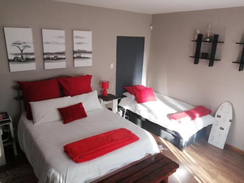 1 dormitorio con 2 camas y almohadas rojas en Triginta en Bloemfontein