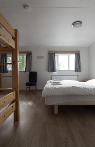 a bedroom with a bed and a chair and two windows at Guesthouse Brekka in Brekka