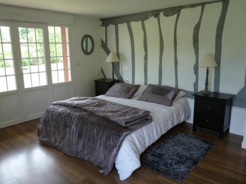 a bedroom with a large bed and two windows at LA CHAUMIERE in Saint-Léger-de-Rotes