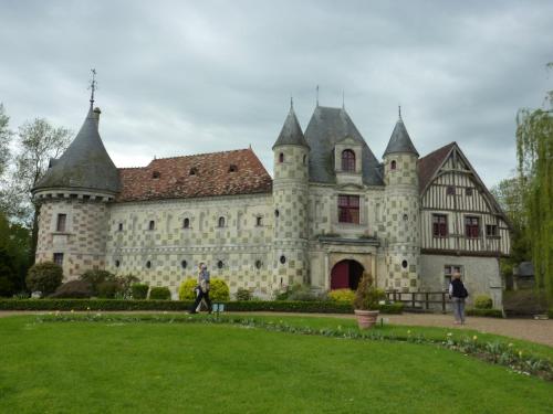 an old castle with a man walking in front of it at LA CHAUMIERE in Saint-Léger-de-Rotes