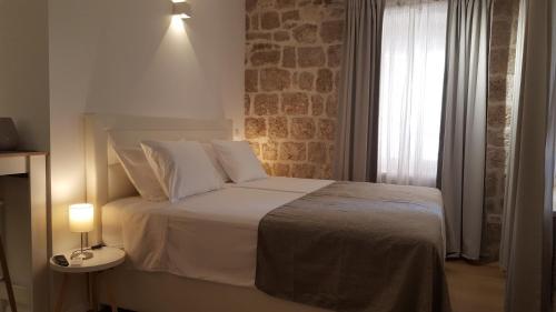 a bedroom with a white bed with a brick wall at Apartments Milion in Korčula