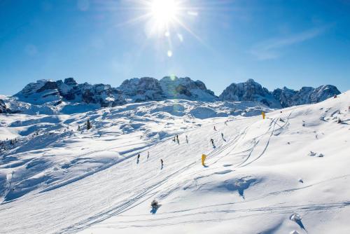 a group of people skiing down a snow covered slope at Hotel Cime D'Oro in Madonna di Campiglio