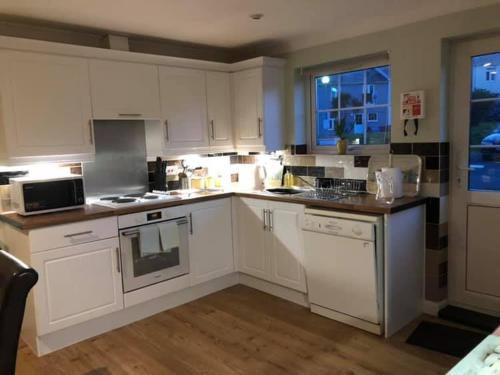 uma cozinha com armários brancos e electrodomésticos brancos em Atlantic Lodge em Newquay
