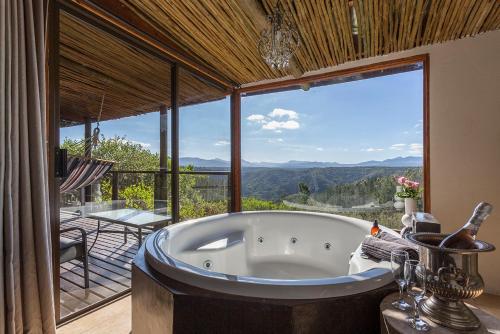 bañera en una habitación con ventana grande en Forest Valley Cottages en Knysna
