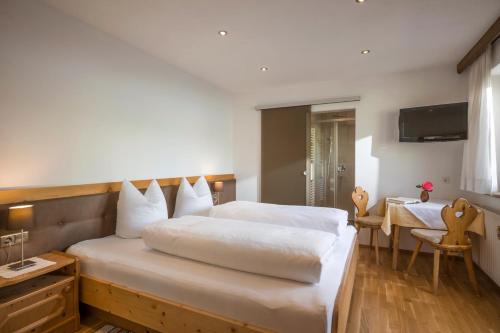 a bedroom with a large bed and a table at Gästehaus Rauch in Schwendau