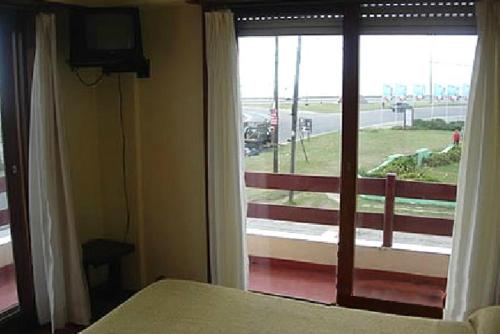 a bedroom with a bed and a window with a view at Hotel Carilo in Mar del Plata