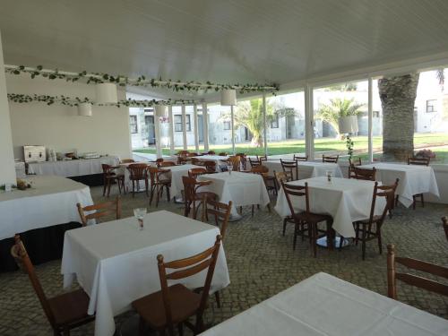 a dining room with white tables and chairs and windows at Hotel Rural Quinta de Santo Antonio in Elvas