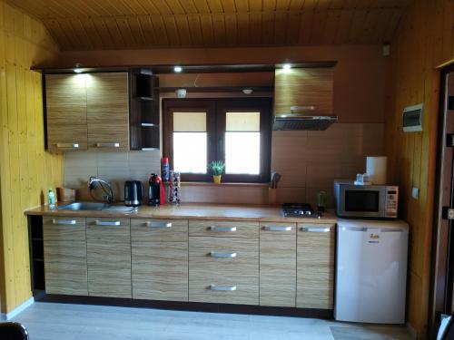 a kitchen with wooden cabinets and a microwave and a refrigerator at Domek letniskowy in Władysławowo