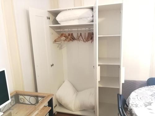 a white closet with a bed and a desk at Studio Résidence le Metropole in La Bourboule
