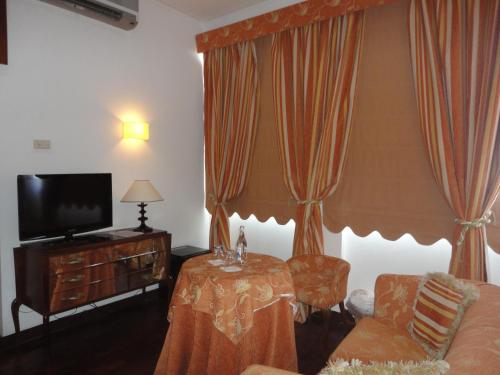 a living room with a table and a tv and curtains at Hotel Rural Quinta de Santo Antonio in Elvas