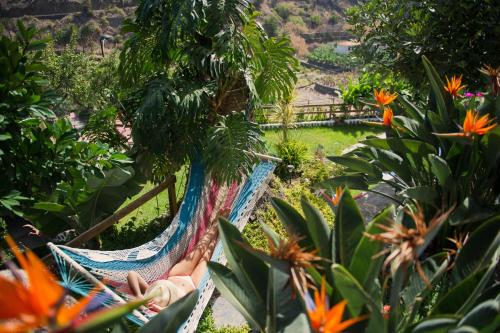 a person sitting in a hammock in a garden at Apartamentos Los Telares in Hermigua