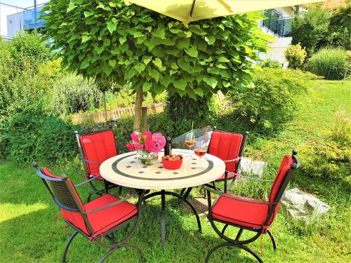 ein Tisch mit vier Stühlen und ein Tisch mit Blumen darauf in der Unterkunft Haus am Weinberg II in Seekirchen am Wallersee