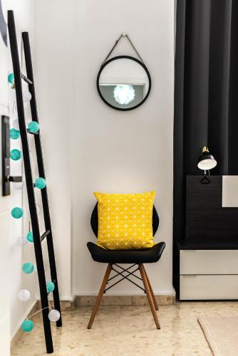 a yellow pillow sitting on a chair in a room at Nordik Rooms Urban - Trinidad "Copenhague" in Málaga
