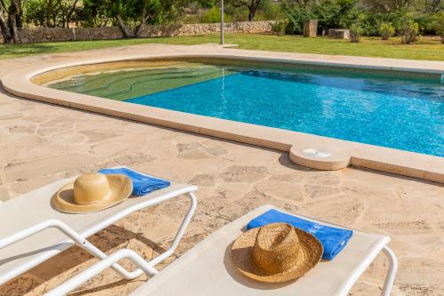 two straw hats sitting on chairs next to a swimming pool at Son Mesquida d'Abaix in Algaida