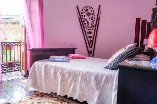 a bedroom with a bed with a pink wall at Pensión Santa Rosa in Samos