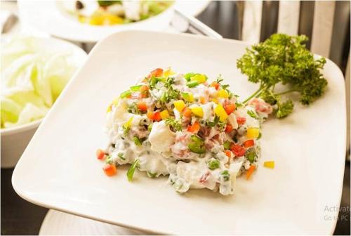 a white plate with a salad with vegetables on it at Royale Exotica, Goa in Calangute