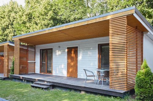 a small house with a wooden deck with a table at Metropolis Domki in Sopot