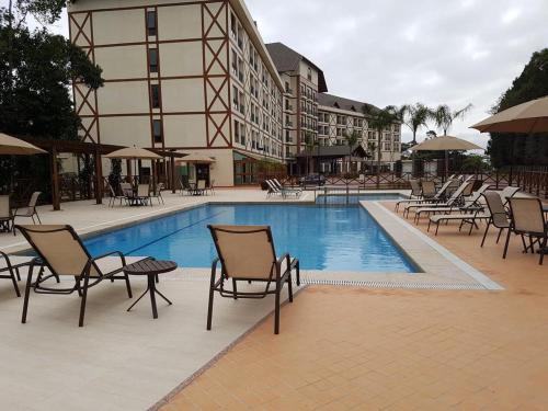 a swimming pool with chairs and tables next to a building at Loft Res Pedra Azul - hospedagem nas montanhas in Pedra Azul