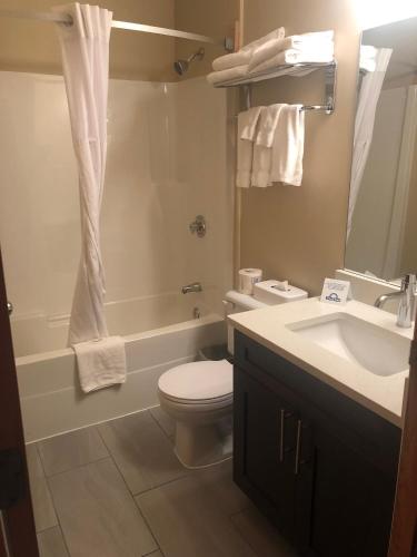 a bathroom with a toilet and a sink and a tub at Days Inn by Wyndham Hinton in Hinton