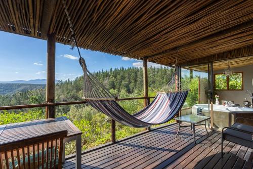 a hammock on the deck of a house with a view at Forest Valley Cottages in Knysna