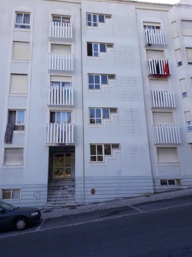 シントラにあるRio de Mouro Quartosの白いアパートメントの建物で、車が正面に駐車しています。
