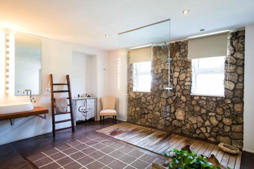 y baño con pared de piedra y ducha. en Luxury Villa Moruse, en Melendugno