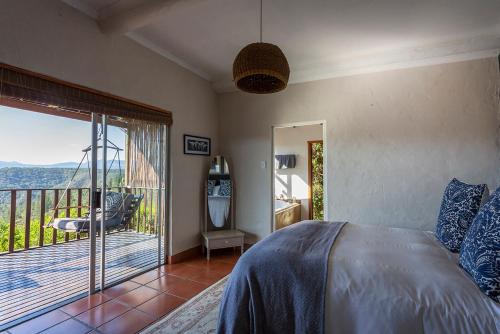 a bedroom with a bed and a balcony at Forest Valley Cottages in Knysna