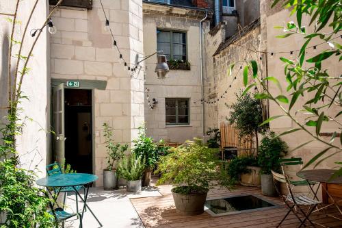 a courtyard with tables and potted plants in a building at Maison Gaspard - Suites et appartements de charme à Saumur in Saumur