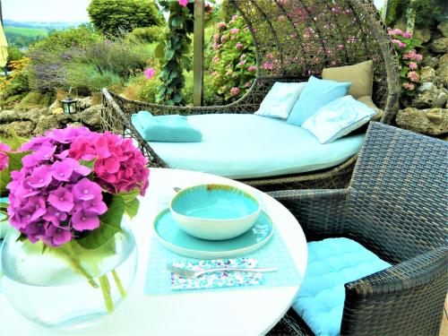 einen Tisch mit einer Vase lila Blumen und einer Couch in der Unterkunft Haus am Weinberg II in Seekirchen am Wallersee
