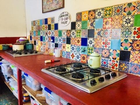 a kitchen counter with a stove and tiles on the wall at Hostel El Nagual in San Cristóbal de Las Casas