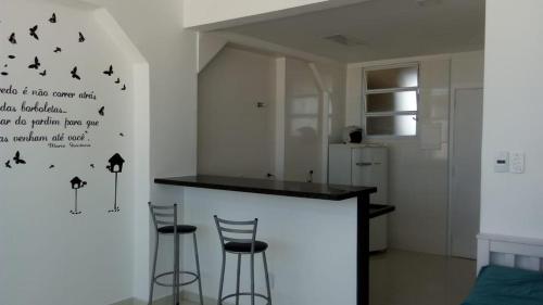 a kitchen with a bar with stools and birds on the wall at AUDAX MARAVILHA in São Vicente