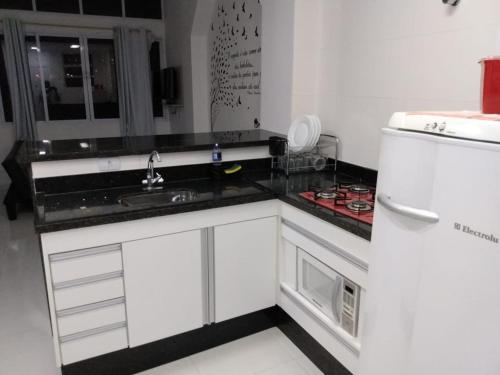 a kitchen with white cabinets and a white refrigerator at AUDAX MARAVILHA in São Vicente