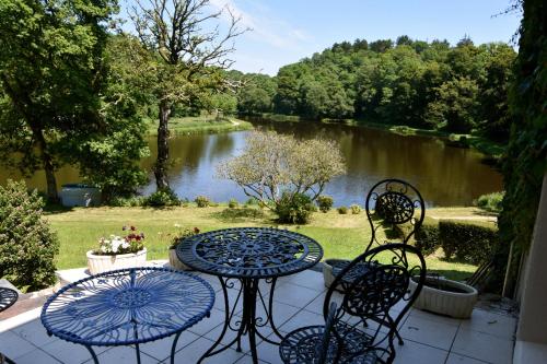 a table and chairs on a patio with a view of a river at Les Etangs de Pitié in Mellionnec