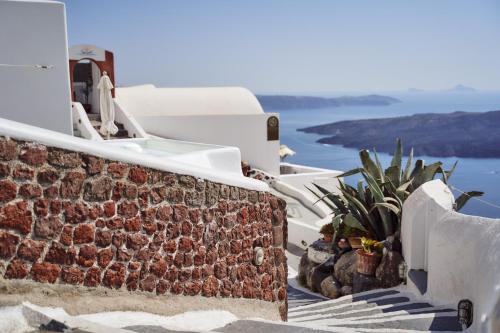 a row of white buildings with plants and water at Mirabo Villas in Firostefani