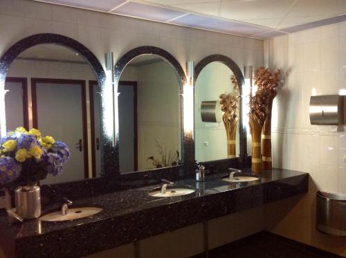 a bathroom with three sinks and three mirrors at SuyderSee Hotel in Enkhuizen
