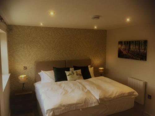 a bedroom with a bed with white sheets and pillows at The Grange Silverstone in Towcester