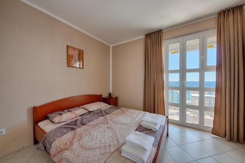 a bedroom with a bed and a large window at XXL Apartments in Dobra Voda