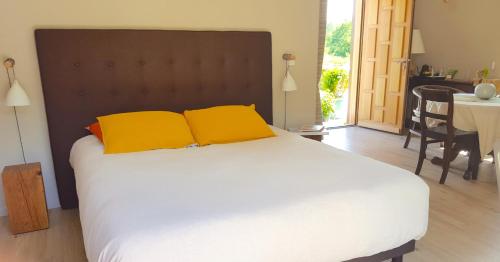 1 dormitorio con 1 cama grande y 2 almohadas amarillas en L'Herbe aux Vaches en Saint-Pierre-Azif