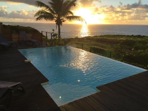 a swimming pool with the sunset in the background at Villa Estheria in Sainte-Anne
