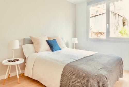 1 dormitorio blanco con 1 cama grande con almohadas azules en Downtown La Torre, en A Coruña