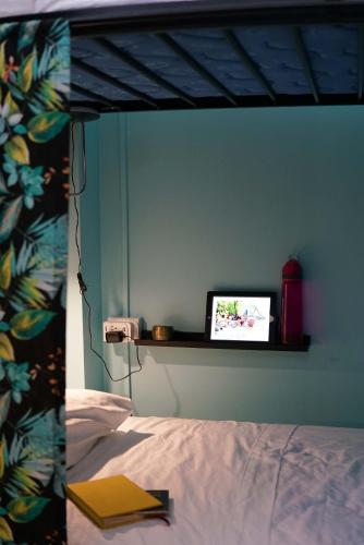 a bedroom with a bed and a laptop on a shelf at NATIVUS Art-Hostel in San José