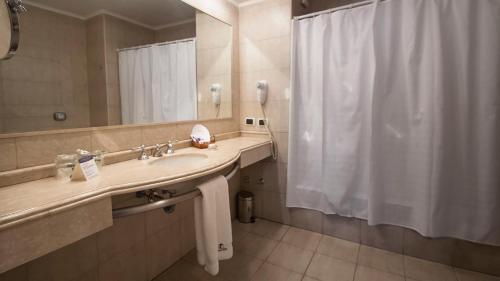 a bathroom with a sink and a shower curtain at Tucuman Center Suites&Business in San Miguel de Tucumán